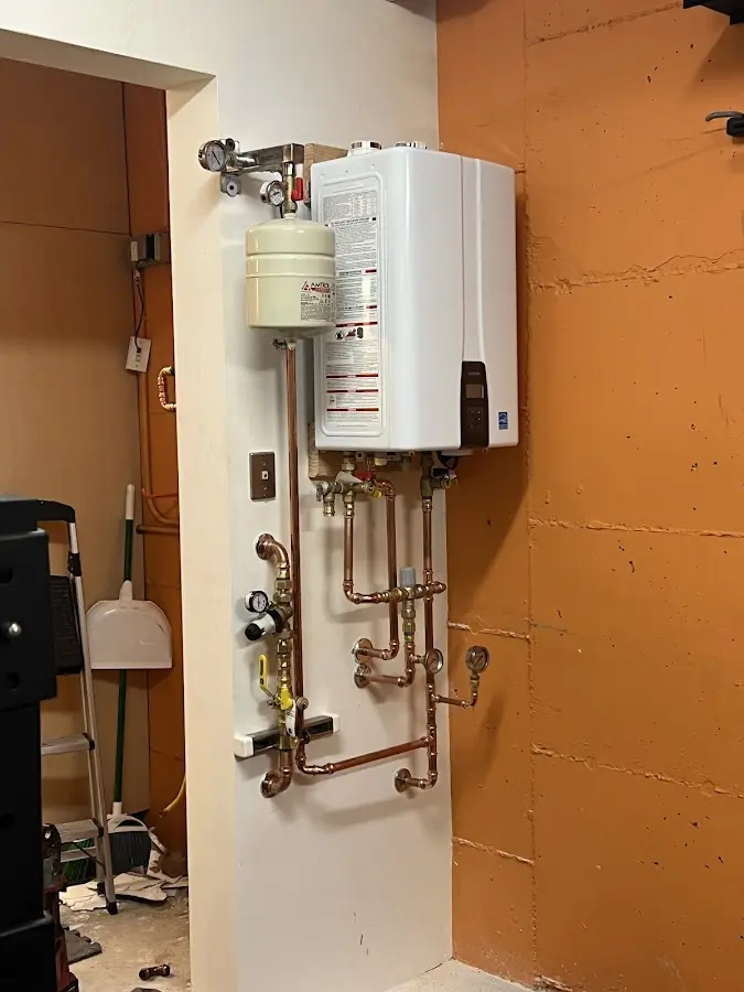 Plumbing technician inspecting water heater connections in Hohenwald